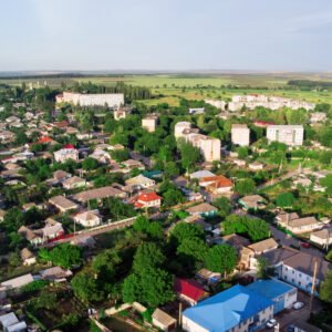 Donduseni with multiple residential buildings and greenery, fields on the background, view from the drone in Moldova